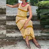 Woman wearing a yellow and brown crochet dress sitting on stone steps.