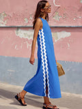 Woman wearing a blue dress with white stripes against a colorful wall.