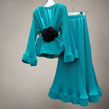 Teal outfit with a black flower detail on a white background