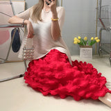 Person wearing a white top and red ruffled skirt sitting on a chair.