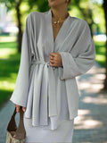 Woman wearing a light gray robe with a blurred outdoor background