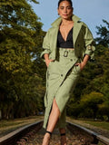 Woman in a green outfit standing on train tracks with trees in the background