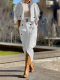 Person wearing a white trench coat with a belt, beige top, and brown boots in an outdoor setting.