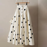 A white polka dot skirt with a high waist and A-line silhouette displayed on a hanger against a plain background.