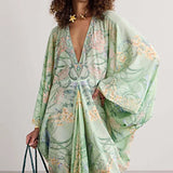 Woman wearing a green floral kimono-style dress against a plain background