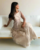 Woman in a white dress sitting on a couch with a neutral background