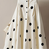 White skirt with black polka dots on a hanger against a neutral background
