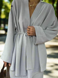 Person wearing a light gray robe with a blurred background