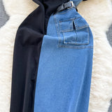 Blue jeans with a black coat on a textured white surface