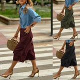Woman crossing a street wearing a blue shirt, maroon skirt, and black pants with gold shoes.